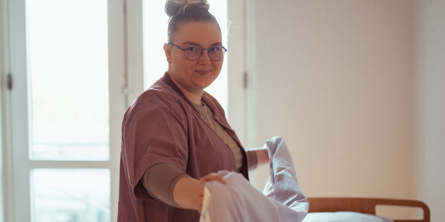 SOSU-elev lægger rent sengetøj på.